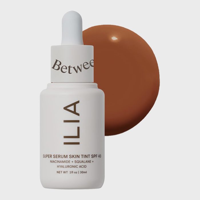 Bottle with dropper displays skincare text, sits beside brown liquid circle, against plain background. Text includes 
