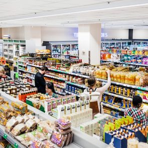 Shoppers browse shelves filled with various groceries in a well-lit supermarket aisles, capturing an everyday shopping scene.