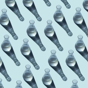 Bottles cast long shadows, arranged diagonally, on a light blue background.