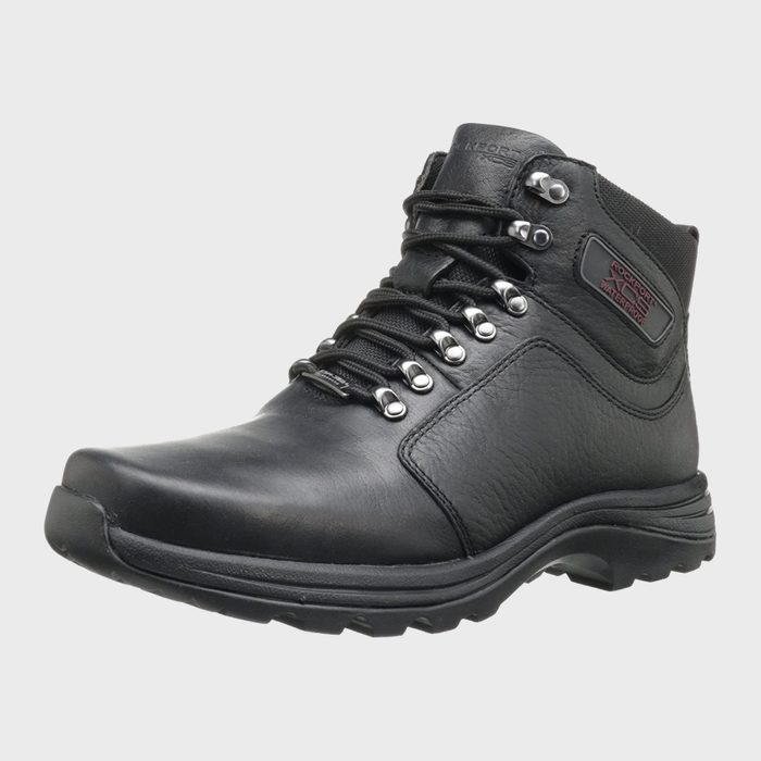 A black leather boot is angled slightly, displaying laced eyelets and rugged sole, in a studio setting. Text reads: 