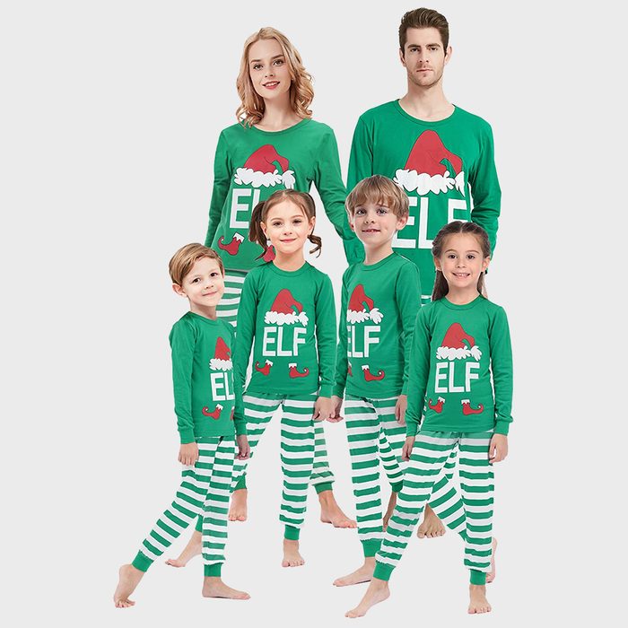 People wear matching green elf-themed pajamas, smiling in a studio setting.