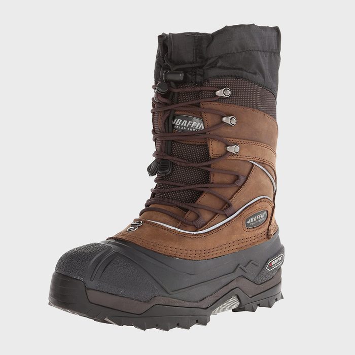 A brown winter boot with laces stands upright against a plain background, featuring rugged soles and black fabric at the top.