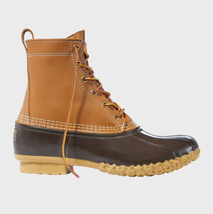 A brown duck boot stands upright with laces undone, featuring rubber soles and leather upper, isolated on a plain white background.