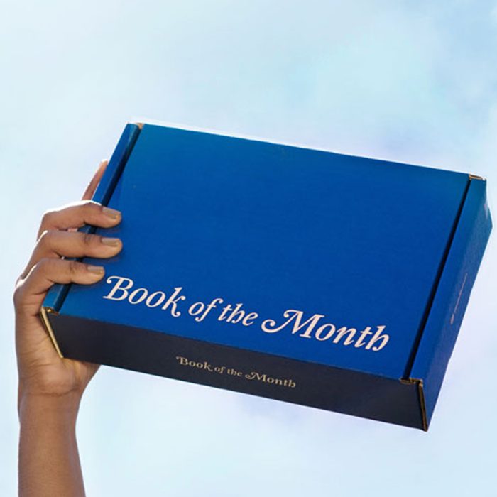A hand holds a blue box labeled 