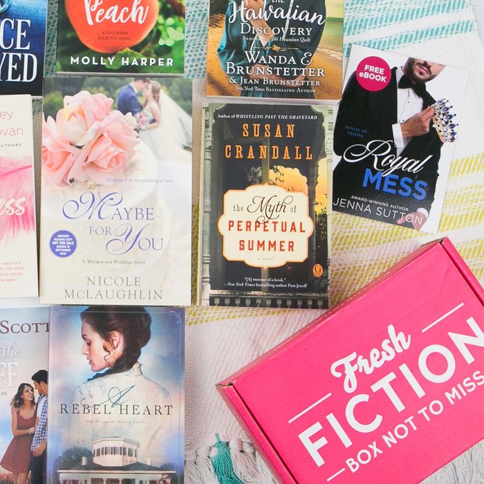 Books arranged on a colorful blanket with a pink 