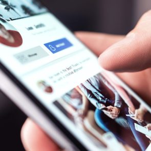 Smartphone displays a social media profile, thumb scrolling, in a close-up shot. Text includes options like 