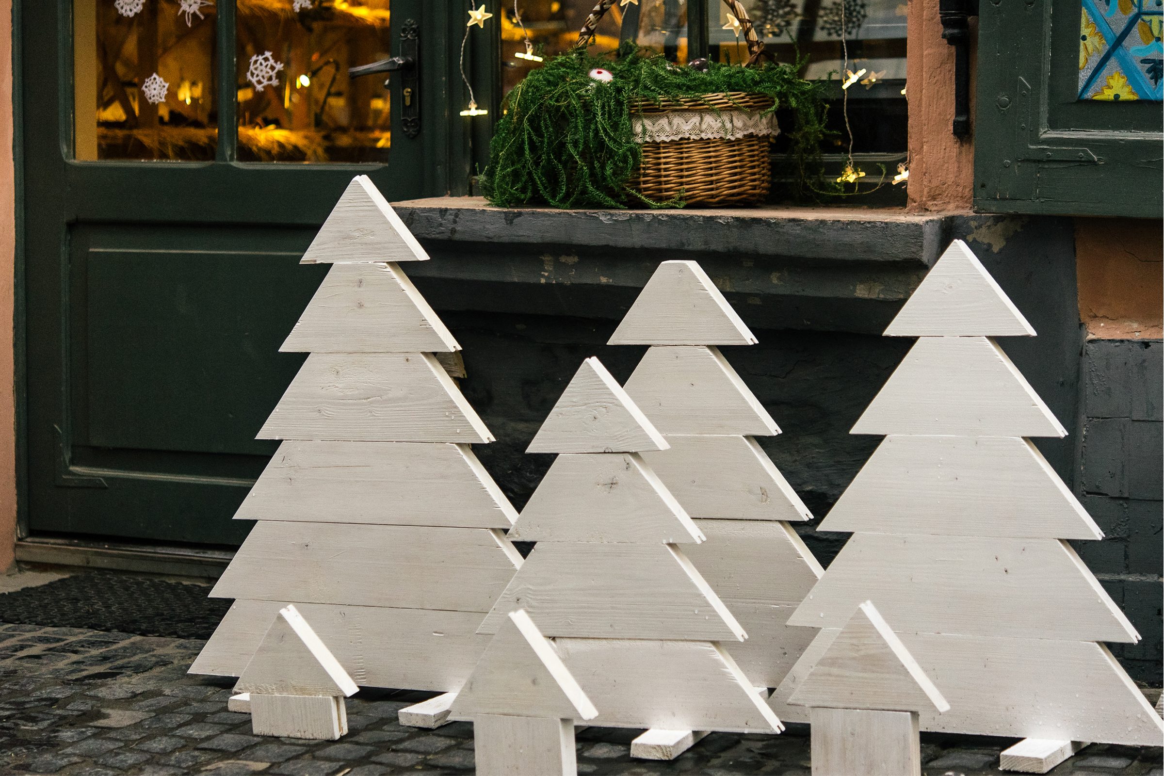 stylish simple wooden christmas trees and garland lights, celebration decoration for holidays in the city.