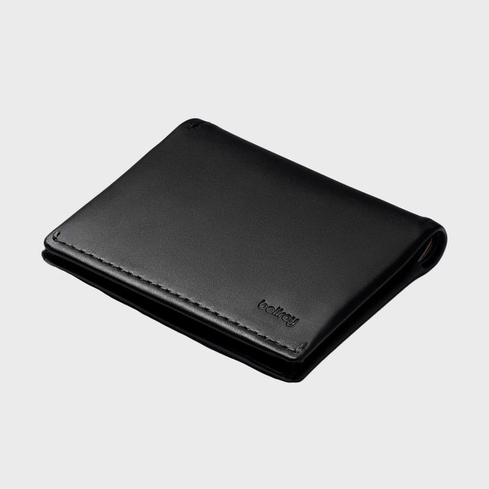 A black leather wallet lies closed against a plain gray background with 