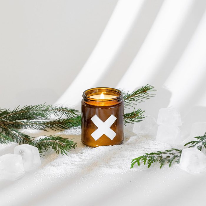Candle burns in a brown jar marked with an 
