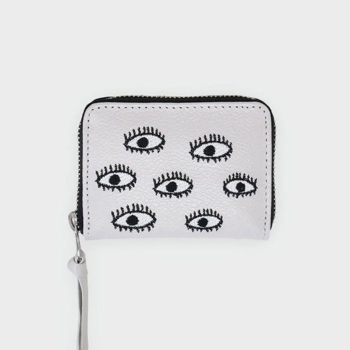 A white zippered wallet displays black embroidered eyes, arranged in two rows, against a plain background.