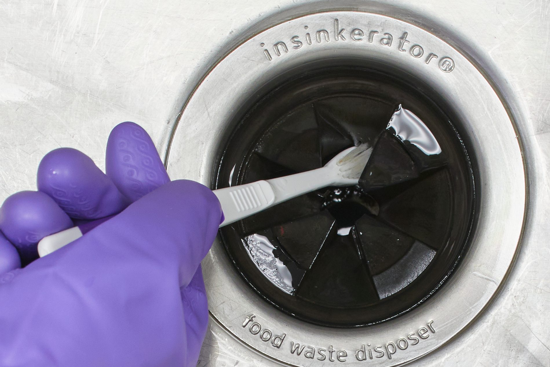 cleaning garbage disposal with a tooth brush