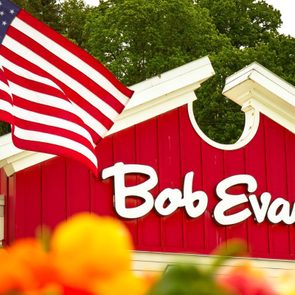 American flag waves above red building reading 