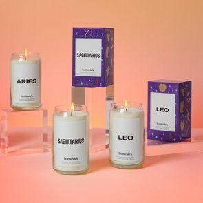 Candles labeled Aries, Sagittarius, and Leo burn on clear stands. Decorative boxes with zodiac symbols surround them on a warm gradient background.