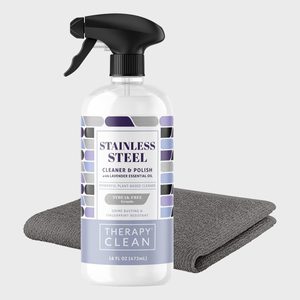 Spray bottle holds stainless steel cleaner; rests on a gray cloth in a minimal setting. Text: 