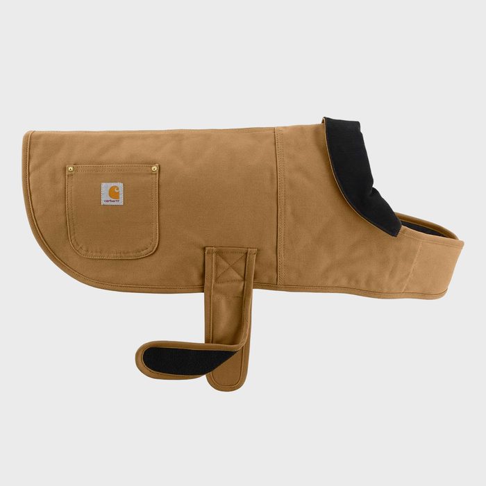 Dog coat laying flat, showing a pocket with logo; designed for warmth, the coat has straps and a tan color, set against a plain background.