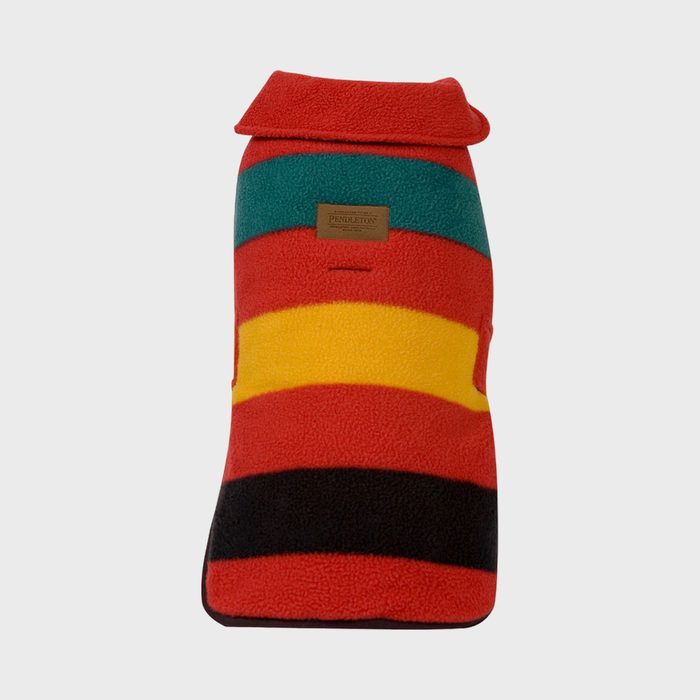Fleece dog coat features colorful horizontal stripes and a small leather label, set on a plain gray background.