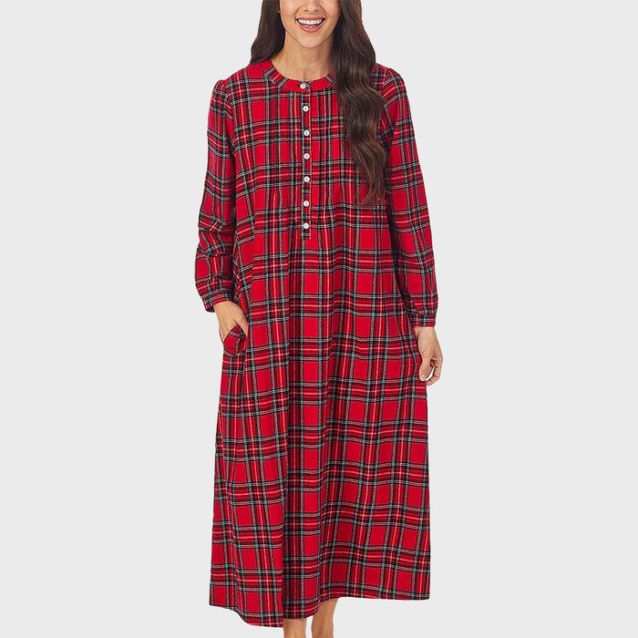 A person wears a red plaid, long-sleeved dress with buttons, standing against a plain white background.