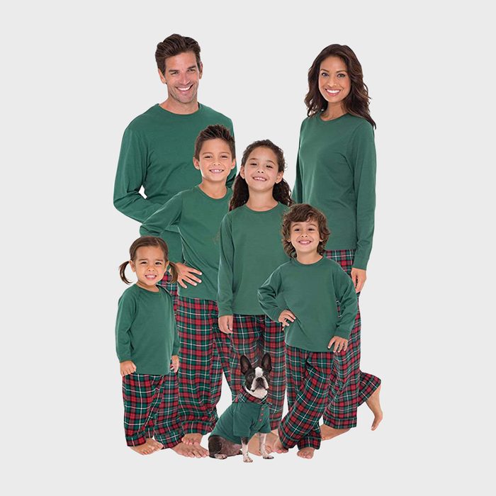 Family wearing matching green shirts and plaid pants, posing together with a dog in similar attire, on a plain white background.