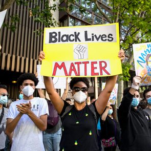 Protesters hold signs reading 
