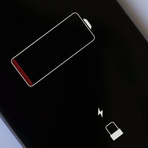 Low battery icon displaying minimal charge, accompanied by a charging symbol and lock icon, on a dark screen background.