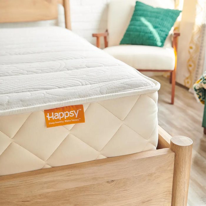 Mattress sits on wooden bed frame, with a tag reading 