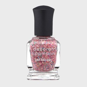 Nail polish bottle sits upright, displaying glittery pink liquid, labeled 