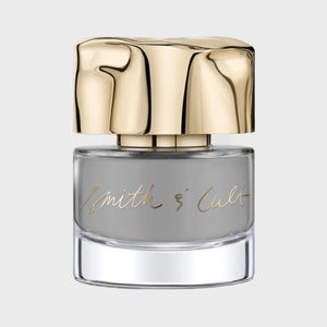 A gray nail polish bottle with a shiny gold cap, labeled 
