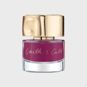 A glass bottle displays purple nail polish with a gold, reflective cap and 