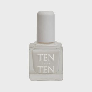 A bottle of white nail polish stands upright on a plain background. The bottle reads 