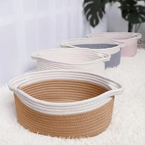 Four woven baskets sit in a row on a fluffy white rug, with greenery in the background.
