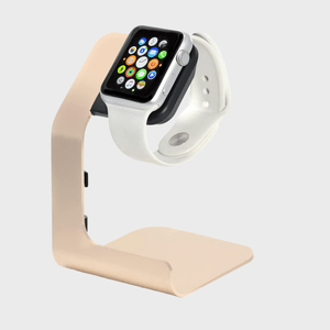 A smartwatch with a white band rests on a beige stand, set against a plain gray background.