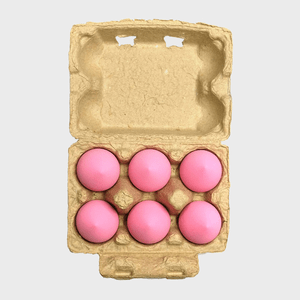 Six pink eggs rest in an open cardboard carton against a plain white background.