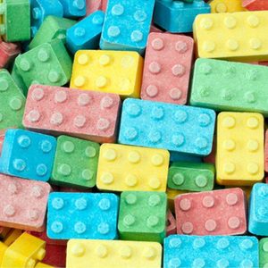 Colorful candy blocks, resembling toy bricks, are scattered in a pile, showcasing various pastel hues like blue, yellow, pink, and green.