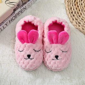 Fluffy pink slippers resemble sleeping bunnies, resting on a white textured rug beside a woven basket.