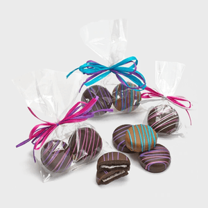 Cookies sit wrapped in clear bags, adorned with colorful ribbons; some cookies are unwrapped, revealing chocolate coating with vibrant icing stripes.