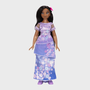 Doll stands upright, wearing a purple floral dress with layers; a pink flower adorns her hair in a plain, neutral background.