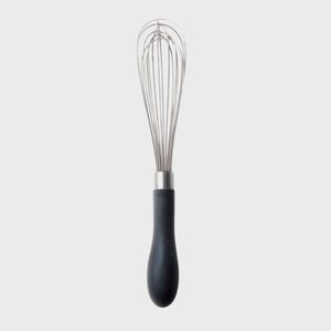 Whisk is upright against a plain background, featuring a black handle and metallic wires for mixing ingredients.