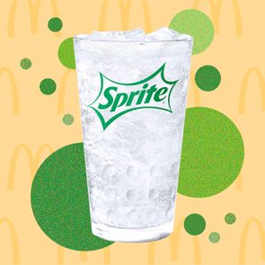 A glass of Sprite with ice, set against a playful background featuring green and yellow circles and McDonald's arches.