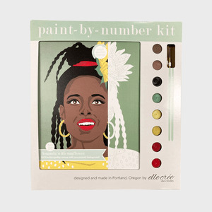 Paint-by-number kit depicting a woman with sunflower, surrounded by six paint pots and brushes, on artist-quality green canvas packaging.