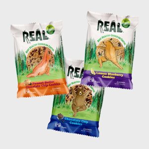 Three cookie packs display animal designs, showing flavors: Peanut Butter Chocolate Chip, Lemon Blueberry, and Chocolate Chip against a green forest backdrop.