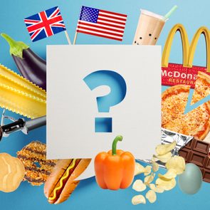 Question mark on paper surrounded by various foods and flags, including pizza, chocolate, and bubble tea against a blue backdrop.