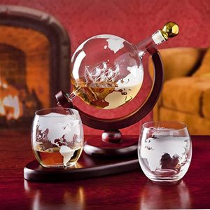 A globe-shaped decanter holds whiskey, resting on a wooden stand, with two matching etched glasses nearby; fireplace and sofa in the background.