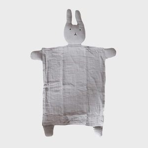 A plush bunny-shaped comforter lies flat on a plain background, featuring a fabric body with a simple, stitched face.