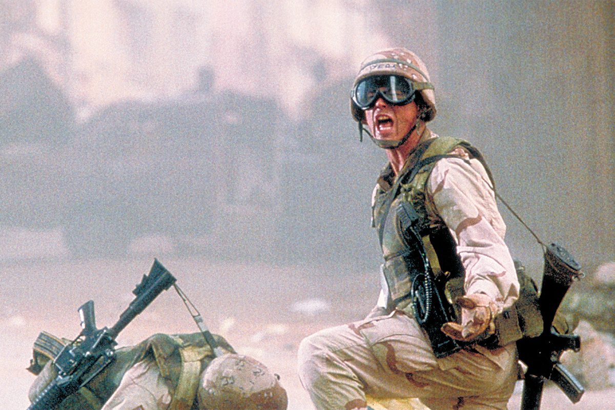 Soldier kneels and shouts, holding a rifle. Dusty, chaotic battlefield environment with blurred tanks in the background.