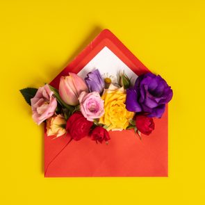 A red envelope holds colorful flowers, including roses and tulips, against a bright yellow background.