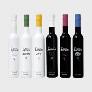 Bottles stand upright, displaying a variety of olive oils and vinegars, each bottle with a distinct colored cap and label on a neutral background.