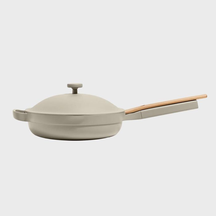 Pan with lid sits idle; features a sleek design and a wooden handle; background is plain white.
