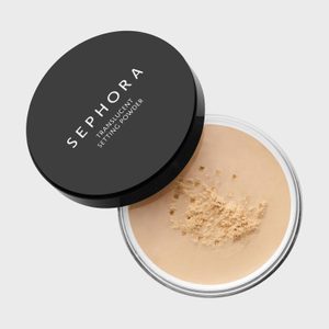 Container holds translucent setting powder, scattered across its surface. Black lid reads 