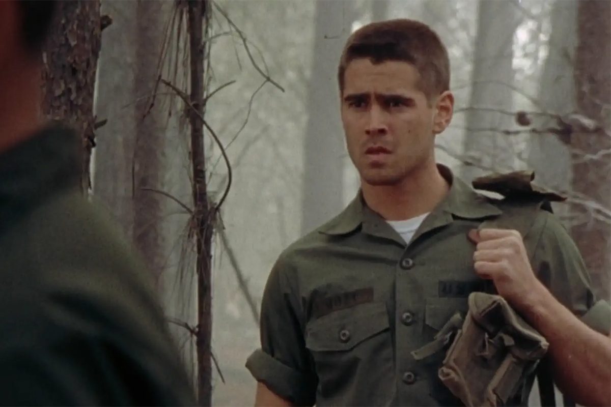Man in uniform holds a bag, standing tensely in misty forest with sparse trees, exuding a sense of determination and focus.