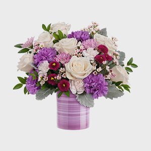 Flowers arranged in a purple vase; white roses, purple carnations, and greenery create a colorful, elegant bouquet against a plain background.